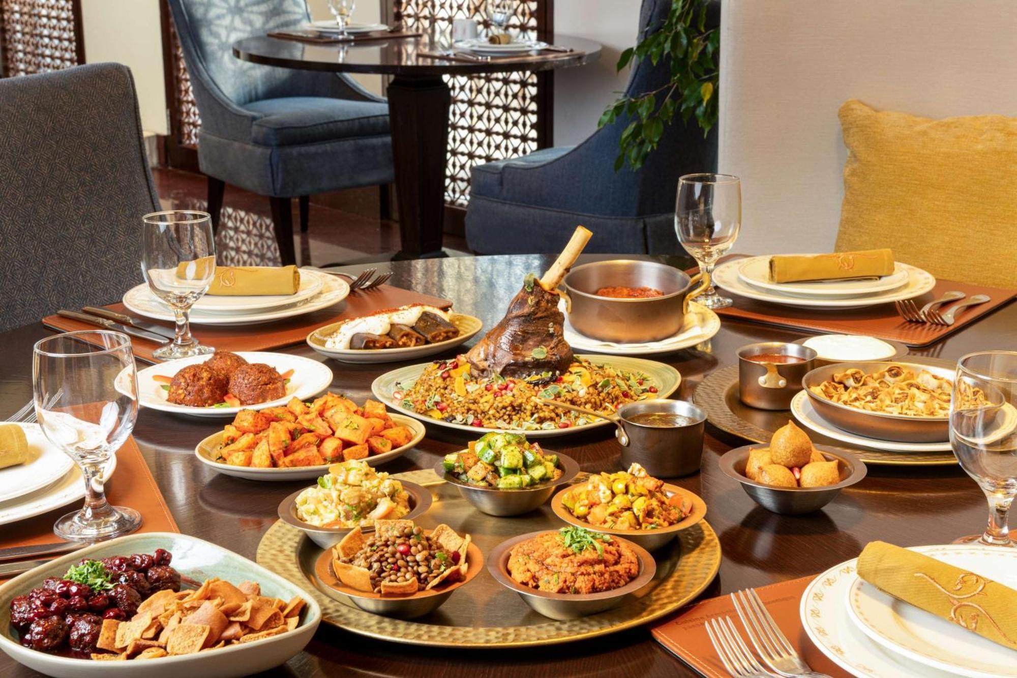 Hilton Riyadh Hotel & Residences Ngoại thất bức ảnh The photo depicts a beautifully arranged dining table featuring a variety of dishes. There are several large plates filled with different foods, including a prominent dish at the center that appears to be rice and meat, likely a type of biryani or pi