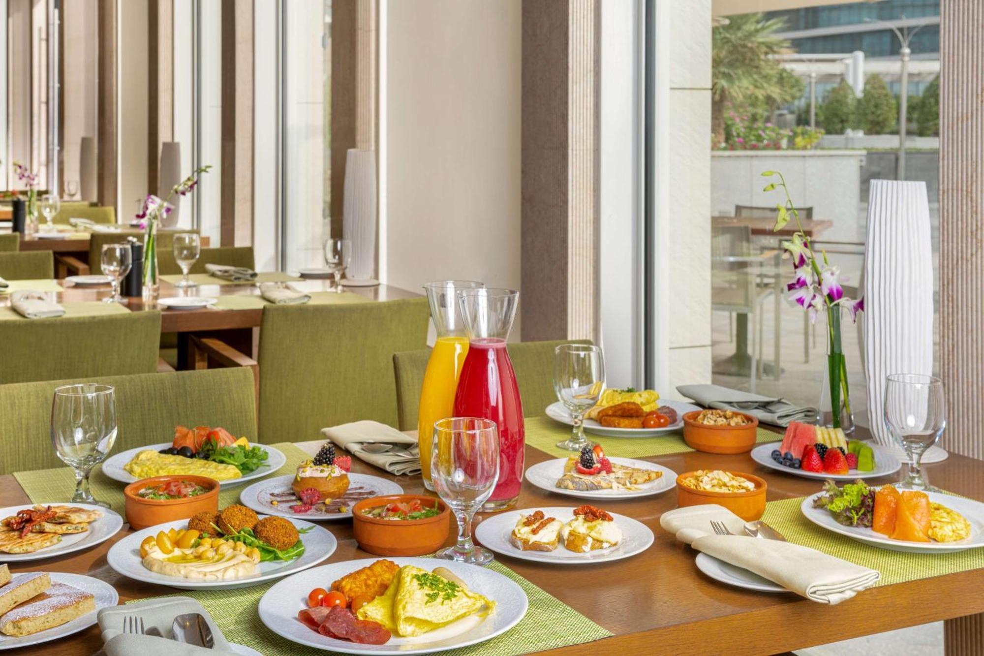 Hilton Riyadh Hotel & Residences Ngoại thất bức ảnh The photo showcases a beautifully arranged dining table filled with a variety of dishes. There are multiple plates featuring an assortment of foods, including salads, appetizers, and main courses, presented in a vibrant and appetizing manner. Additio
